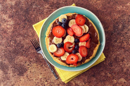 High angle view fruit waffle with chocolate spread and a forkの写真素材
