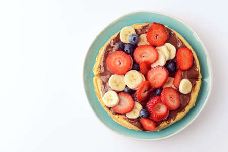 blue plate with mixed fruit and chocolate spread on waffleの写真素材