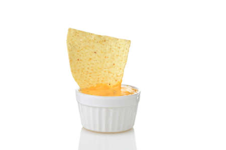 closeup nacho chip dipped in small bowl of spicy cheeseの写真素材