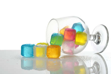 spilled colored plastic ice cubes in brandy glassの写真素材