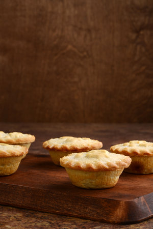 fresh baked christmas mincemeat pies in a row on wood cutting boardの写真素材