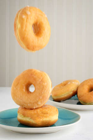 closeup of honey glazed donuts falling on plateの写真素材