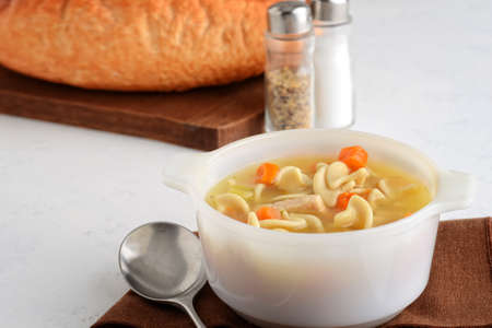 closeup turkey noodle soup with carrots in a white bowl on a brown napkinの写真素材