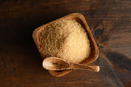 high angle view yellow raw sugar with spoon on wood tableの写真素材
