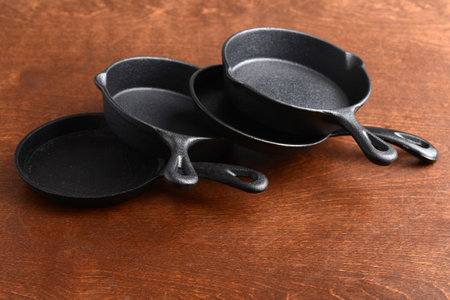 cast iron frying pans piled on wooden tableの写真素材