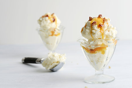 scoops of vanilla ice cream with pecans and caramel sauceの写真素材