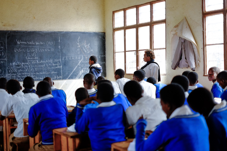 Kibuye/Rwanda - 08/26/2016: Teacher and pupils at mathematics lesson in a classroom in a school in Africa. A blackboard and cross can be seen in the background.のeditorial素材
