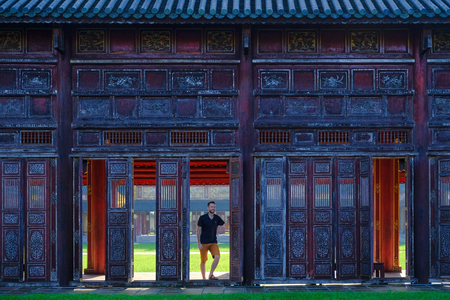 Hue / Vietnam, 17/11/2017: Man standing next to  ornamental doors in a traditional pavillion in the Citadel complex in Hue, Vietnam.のeditorial素材