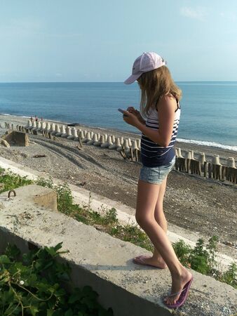 Chemitokvadzhe, Russia-June 23, 2019: a teenage girl stands on the stone slabs on the background of the Black sea.のeditorial素材