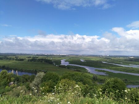 rustic industrial landscape, view from the hill to the valley of the Oka river, on the horizon the outlines of the city, the stormy sky stretched over the field, natural space and perspectiveの写真素材