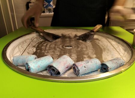 blurred, selective focus. Thai fried ice cream, the process of cooking, mixing, freezing and forming ice cream rolls, decoration and raskryvanie in a paper bowlの写真素材