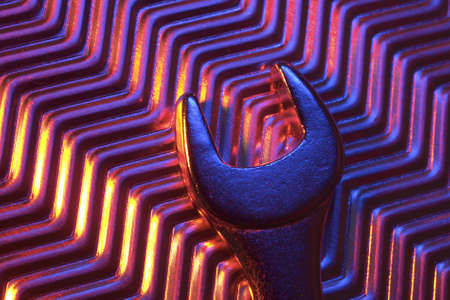 Close-up of metal plate and wrench under low light.の写真素材