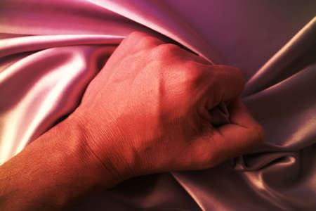 Man grabing satin sheet on the bed.の写真素材