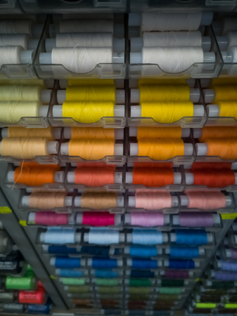 Many threads of different colors on plastic bobbins for sewing, for needlework. Abstract background with colorful spools.の写真素材