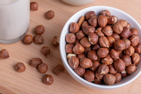 Glass of Hazelnut milk and bottle and organic hazelnuts on wooden background, Alternative Milkの写真素材
