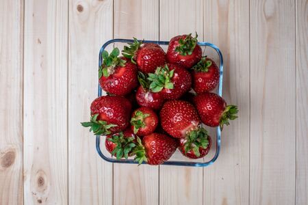 square glass bowl with strawberries on a light wooden table. Big strawberries.の写真素材