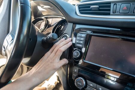 woman push the start button of the engine in her new car. bought car from Auto dealer.