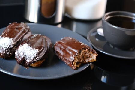 chocolate eclairs on a plate and cup of coffee. traditional fcench Chocolate Eclairs.