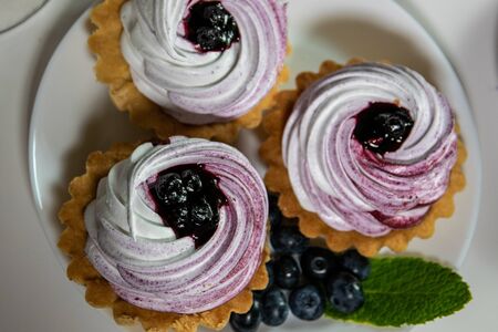 Sweet tartlet with meringue and huckleberry jam and bouquet of phlox on white background closeup.の写真素材