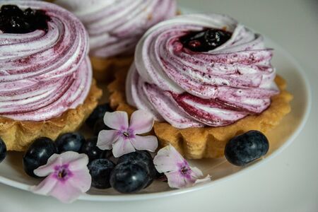 Sweet tartlet with meringue and huckleberry jam and phlox flowers on white background closeup.の写真素材