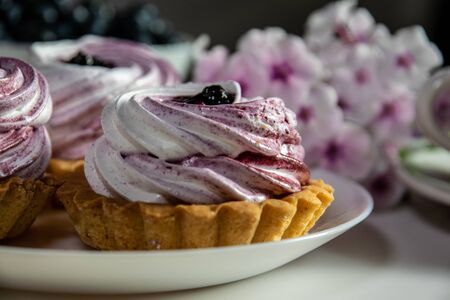 Sweet tartlet with meringue and huckleberry jam and bouquet of phlox on white background closeup.の写真素材