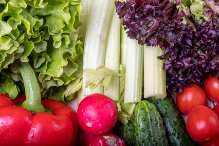 fresh vegetables on a light wooden table, red paprika, celery, leaves of lettuce, tomato cherry,...
