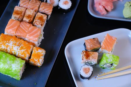 Sushi roll with seafood and soy sauce, wasabi and ginger. Sushi roll with salmon and flying fish caviar on a black table.の写真素材