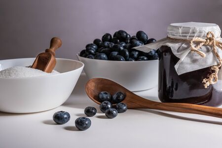 Huckleberry Jam close-up. Blueberry and sugar and wooden spoon in a bowl in the kitchen.の写真素材