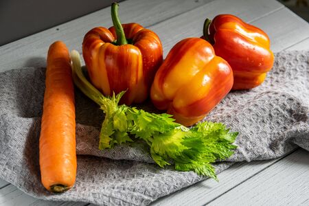 fresh vegetables on a light background. orange carrot, two-tone paprika, red tomato and salad on the kitchen table.の写真素材