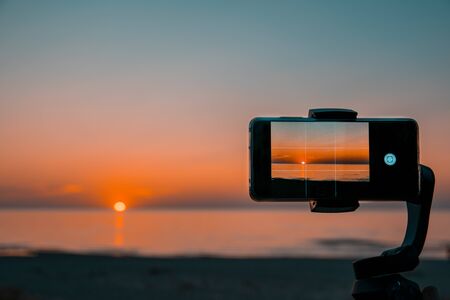 view of a beautiful sunset on the sea through a mobile phone.の写真素材