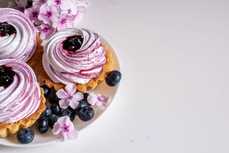Sweet tartlet with meringue and blueberry and huckleberry jam and phlox flowers on white background closeup.の写真素材