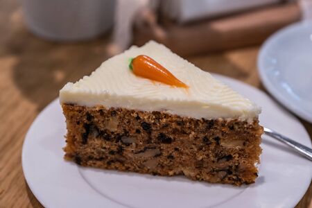 A carrot cake on a white plate in a cafe.の写真素材