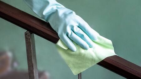 Closeup view of a woman's hand using an antibacterial wet wipe for disinfecting the railing on the...