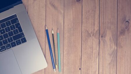 top view of wooden office desk top view with blank laptop and pencils.の写真素材