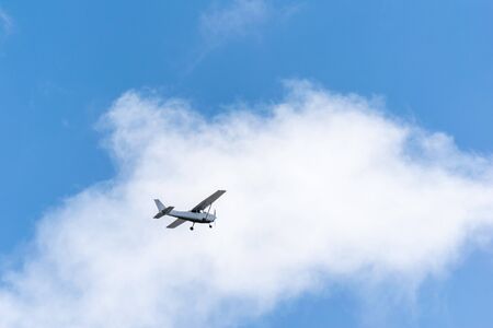 Single piston gray aircraft. Single-propeller aircraft flies over the blue sky against on white...