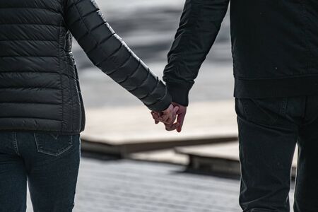 Young happy couple holding each other's hands walking on a city street.