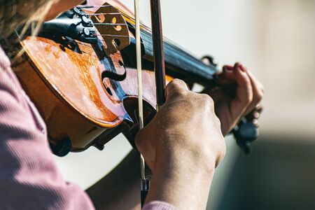 girl plays the violin. Close-up of girls hands and violin strings.の写真素材