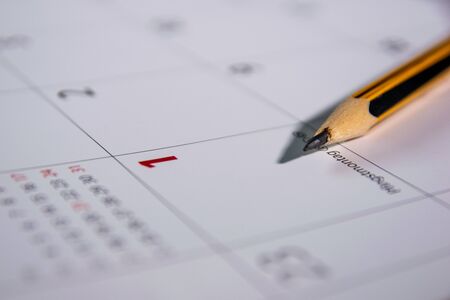 Pencil lies on an open calendar indicating the first day of the month.