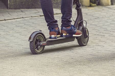 Alternative transport concept. The young man is riding on the electric scooter through the modern...