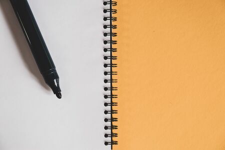 blank spiral notebook and felt-tip pen isolated on a yellow background. business or education...