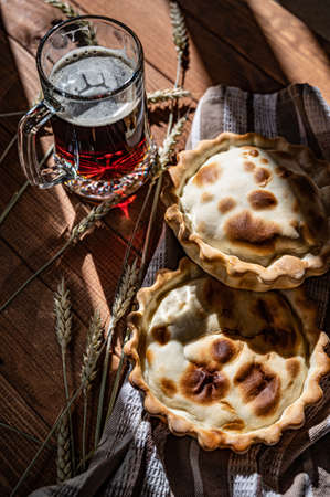 A glass of dark beer and a couple of meat patties on the table in backlight.の写真素材