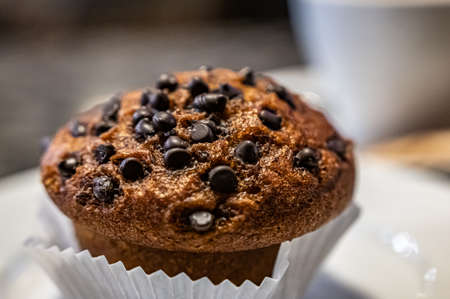 Cup cake topping with shocolate and Nuts on the white plate in a cafe during coffee break.