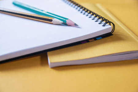 Pen and pencil in a diary, a book on the desktop at the workplace.