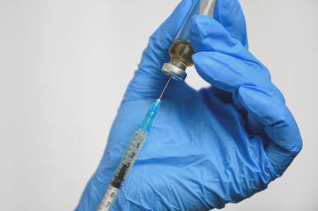 a hand in medical gloves disposes of drugs, a vial and a needle on a syringe, the concept of a vaccine.の写真素材
