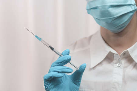 A medical worker holds a syringe with a vaccine in his hand, an injection of medicine. The doctor is going to inoculate.の写真素材