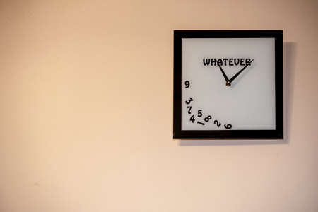 a square clock without numbers hangs on the wall. A watch with an inscription whatever.