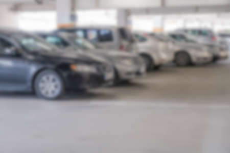 Blur image of cars parked in the parking lot of a multi-storey supermarket