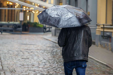 Man with an umbrella in the city. Back view of busy man in rainy weatherの写真素材
