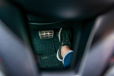 Close-up foot in sports shoes presses on the pedal in the carの写真素材