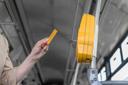 a woman pays with a plastic card for travel in public transport in a bus, tram or metroの写真素材